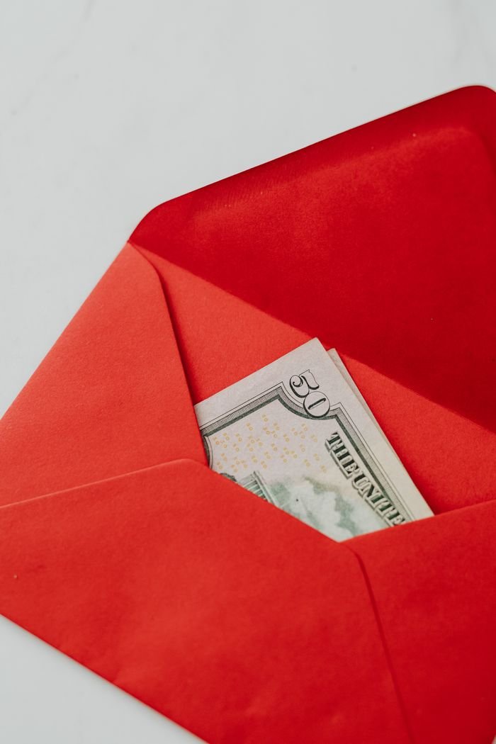 home-hero An open red envelope containing US dollar banknotes, symbolizing financial gifting or saving.
